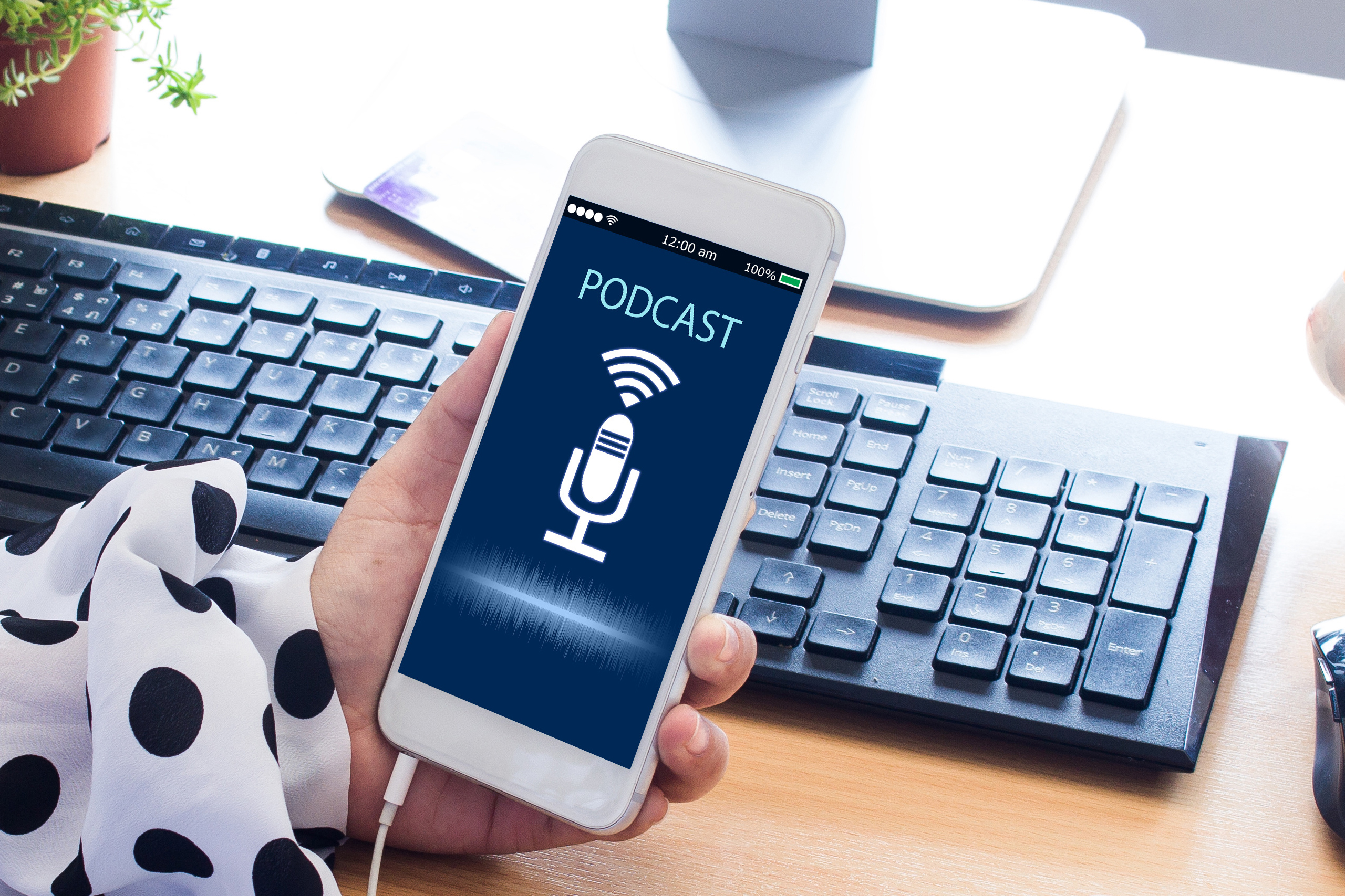 Person holding a smartphone with a podcast playing, symbolizing easy access to spiritual reflections and teachings.